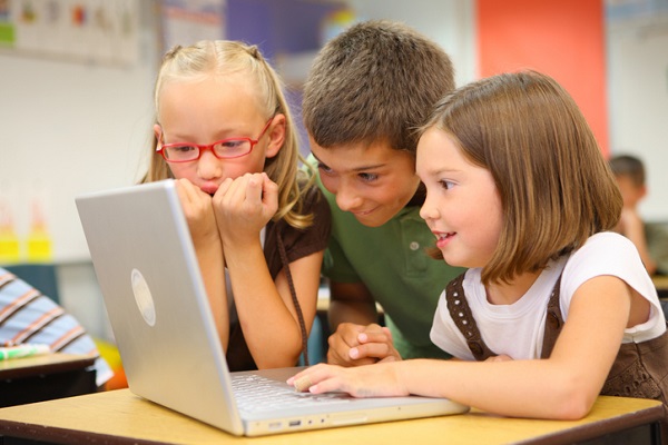 Elementary school students look at laptop computer