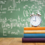 clock on stack of books with chalkboard in background